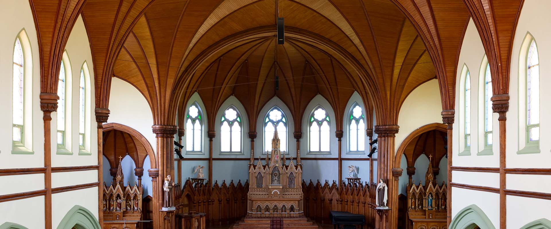 An interior view of St. Mary's Roman Catholic Church in Indian River, Prince Edward Island, looking from the rear of the church towards the altar and highlighting the wooden arch ceiling.